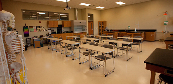 A new science lab with a skeleton in the foreground, tables, chairs and lab equipment.