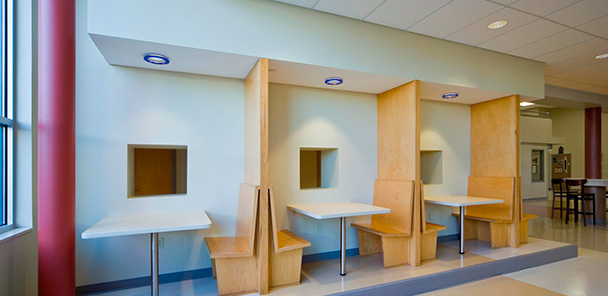 Student work areas with booths of blonde wood divided by large blonde wood dividers and lighting.
