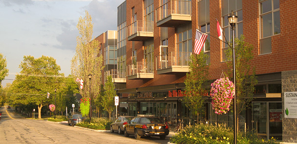 A three story building with brick and metal details, metal balconies, and tree lawn landscaping.